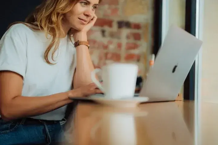 A lady sits in a cafe working on updating the content in her business's knowledge base